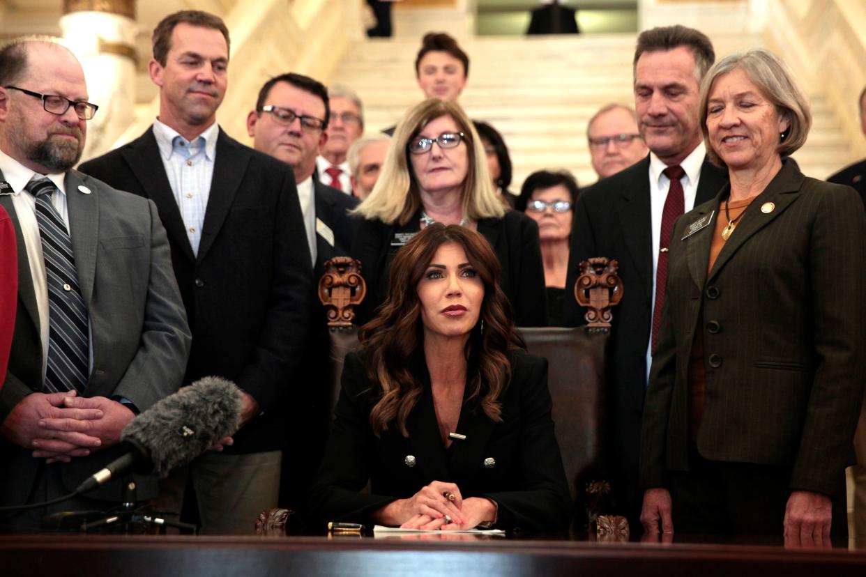 South Dakota Gov. Kristi Noem signs a bill Thursday, Feb. 3, 2022, at the state Capitol in Pierre, S.D., that will ban transgender women and girls from playing in school sports leagues that match their gender identity.