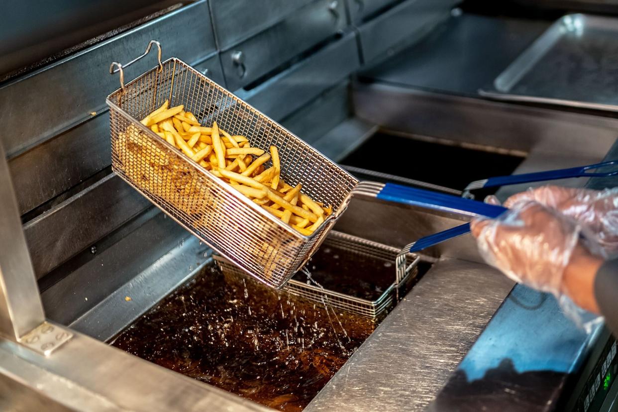 A fast food worker frying french fries