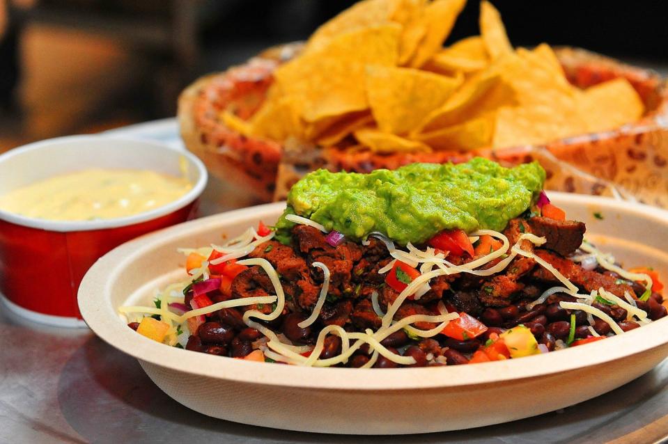 A Chipotle burrito bowl, decorated with fries and a dipping sauce. 