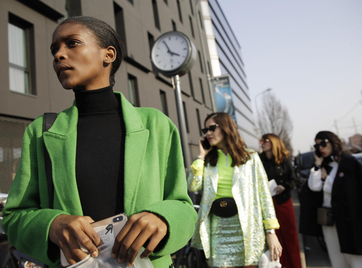 In this picture taken on Tuesday, Feb. 20, 2019, a model and bloggers stand after the Gucci women's Fall-Winter 2019-2020 fashion show, that was presented in Milan, Italy. Fashion is a creative endeavor with no real boundaries, and outside each luxury runway venue, vibrant scenes unfold amid the confluence of influencers, fashion editors, celebrity guests, street photographers and hopeful selfie-snappers. (AP Photo/Luca Bruno)