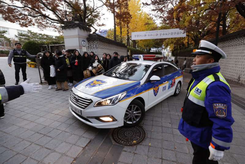 南韓14日舉行大學修學能力試驗，警察忙著把遲到或者忘了帶證件的考生送往考場。（美聯社）