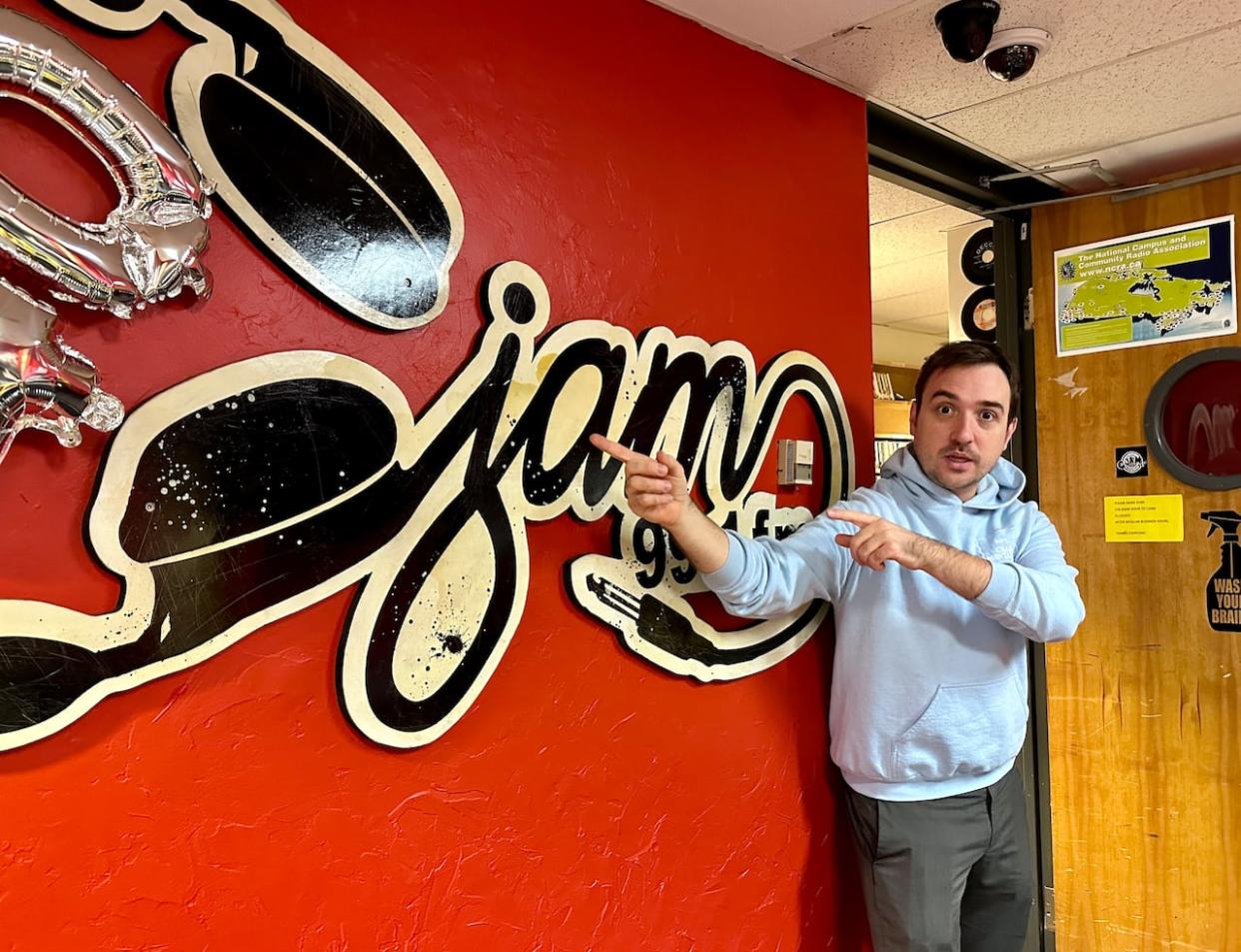 Walter Petrichyn, station manager of CJAM 99.1 FM, gestures at a mural in the station's offices at the University of Windsor student centre. (Dalson Chen/CBC - image credit)