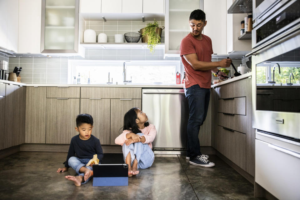 a man cooking and looking down at his kids on the floor