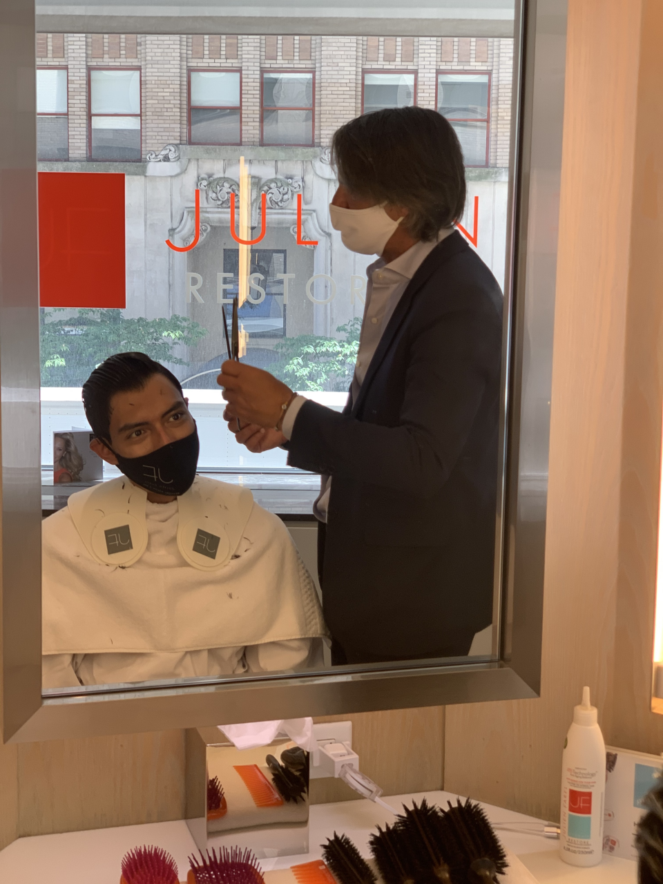 Julien Farel cutting client's hair in newly reopened salon.