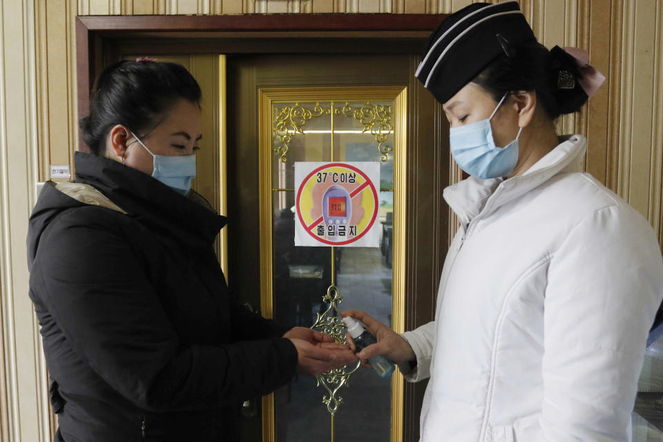 FILE - In this Feb. 5, 2021, file photo, a staff member, right, of the Pongnam Noodle House disinfects the hands of a woman coming into its restaurant in Pyongyang, North Korea. Isolated North Korea has continued to claim a perfect record in keeping out the coronavirus in its latest report to the World Health Organization, on Wednesday, April 7, 2021. At the beginning of the pandemic more than a year ago, North Korea shut its borders and described its efforts to keep out the virus as a “matter of national existence.” It banned tourists, jetted out diplomats and still severely limits cross-border traffic while quarantining tens of thousands of people who have shown symptoms. (AP Photo/Jon Chol Jin, File)