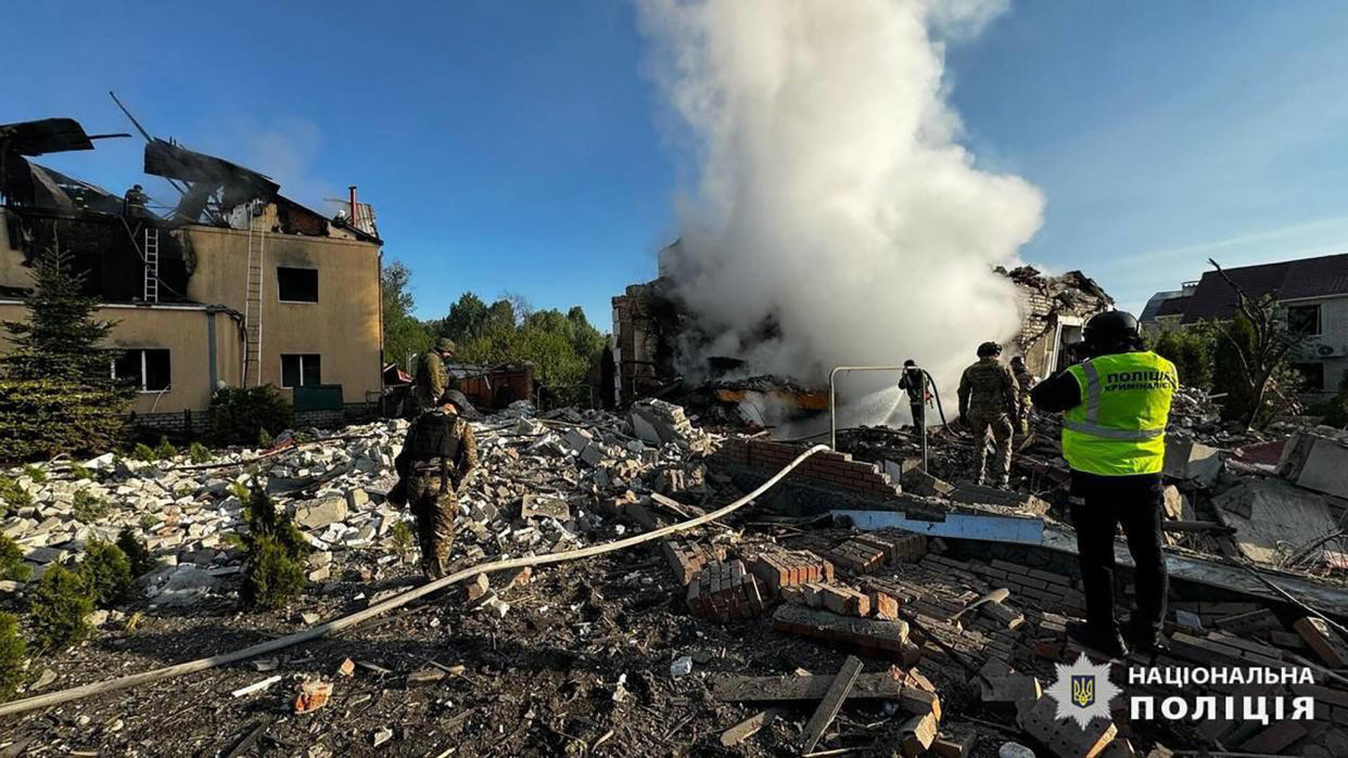 Cette photographie publiée par la police nationale ukrainienne ce vendredi 10 mai montre des employés des services d’urgence éteindre les incendies de maisons détruites par un bombardement à Kharkiv.