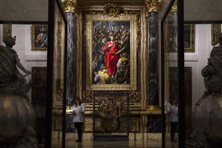 A journalist stands underneath Spanish Renaissance painter El Greco's "El Expolio", or "The Disrobing of Christ", painting during a ceremony marking its return following restoration to the sacristy of the Cathedral of Toledo, January 22, 2014. REUTERS/Paul Hanna