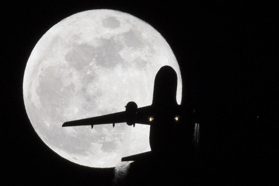 A British Airways Airbus A-319 aircraft from Stuttgart flies in front of a 'super blue moon' on its approach to London Heathrow Airport on January 31, 2018.   
Stargazers across large swaths of the globe -- from the streets of Los Angeles to the slopes of a smoldering Philippine volcano -- had the chance to witness a rare 