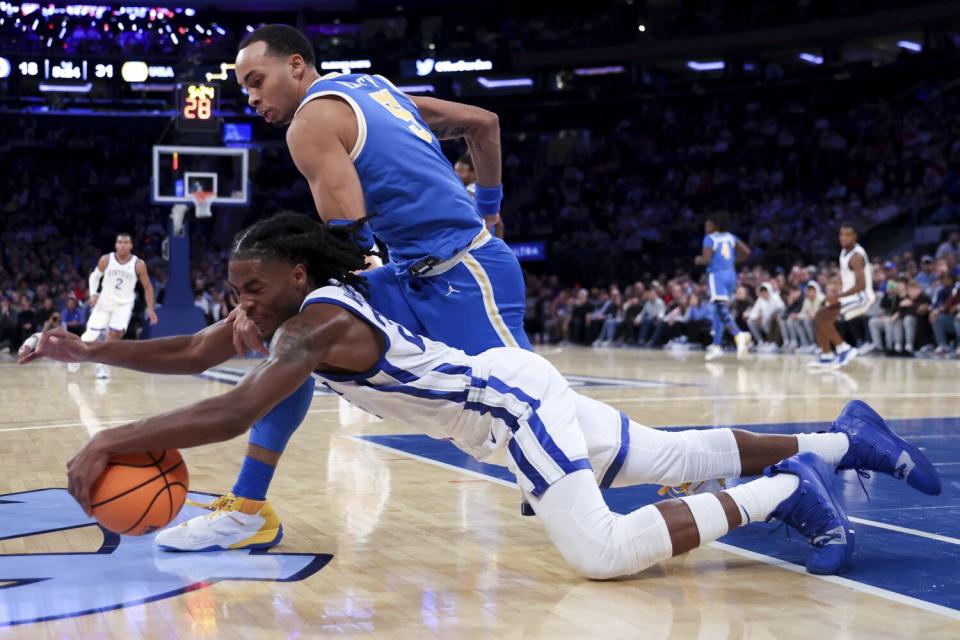 Kentucky guard Cason Wallace, bottom, and UCLA guard Amari Bailey lunge for the ball.