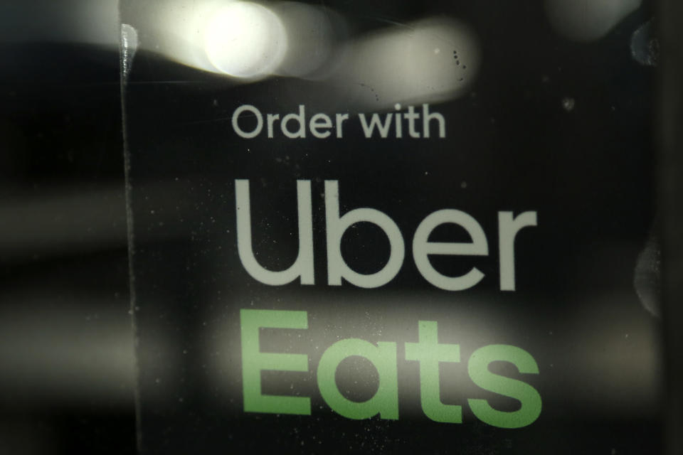 FILE - In this Nov. 6, 2019, file photo, a restaurant advertises Uber Eats in Miami. Restaurant delivery companies like DoorDash and Uber Eats are rapidly expanding their services to grocers, convenience stores, pharmacies, pet stores and even department stores. The move has been spurred by skyrocketing consumer demand during the pandemic. On Wednesday, July 28, 2021 Uber Eats unveiled its newest delivery option that will let users order flowers from FTD directly from its app. (AP Photo/Lynne Sladky, file)