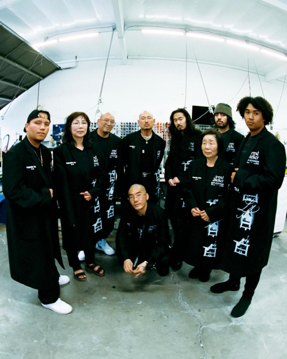 People standing in a semicircle dressed in black Firmé Atelier staff lab coats.