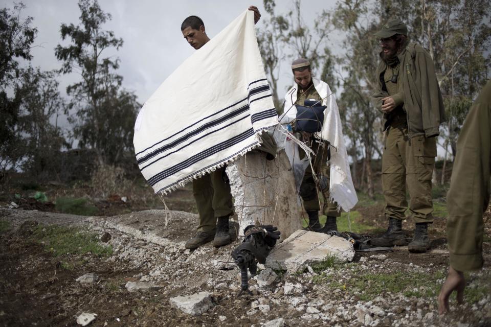 Israeli soldiers of the Golani brigade with prayer shawls after night training near the border with Syria in the Israeli-controlled Golan Heights, Wednesday, Feb. 26, 2014. Hezbollah says Israel carried out an airstrike targeting its positions in Lebanon near the border with Syria earlier this week, claiming it caused damage but no casualties. The Wednesday statement was the group's first acknowledgement of the reported Monday night airstrikes. (AP Photo/Ariel Schalit)