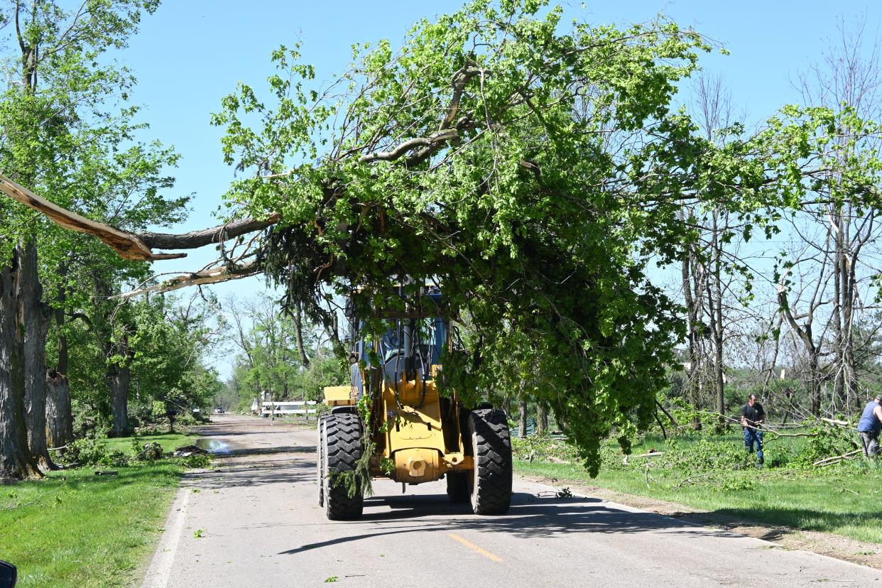 Neighbors used front end loaders to clear trees from tornado hit property along Dunks Road.