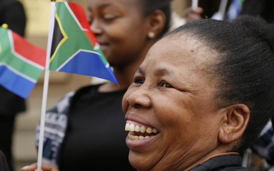 Miniature South African flags are held as Nelson Mandela Foundation's CEO, Sello Hatang, speaks to the press on the steps of the Johannesburg High Court, Wednesday, August 21, 2019. South Africa's Equality Court has restricted the display of the old apartheid-era flag in a ruling issued Wednesday Aug. 21, 2019, that it's gratuitous use amounts to hate speech and racial discrimination. (AP Photo/Denis Farrell)