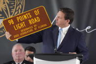 Florida Gov. Ron DeSantis holds up a sign dedicated to the 98 people who lost their lives during a remembrance event at the site of the Champlain Towers South building collapse, Friday, June 24, 2022, in Surfside, Fla. Friday marks the anniversary of the oceanfront condo building collapse that killed 98 people in Surfside, Florida. The 12-story tower came down with a thunderous roar and left a giant pile of rubble in one of the deadliest collapses in U.S. history. (AP Photo/Wilfredo Lee)