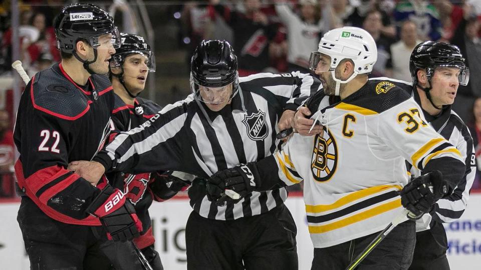 Officials separate Carolina Hurricanesí Brett Pesce (22) and Boston Bruinsí Patrice Bergeron (37) in the first period on Wednesday, May 4, 2022 during game two of their Stanley Cup first round series at PNC Arena in Raleigh, N.C.