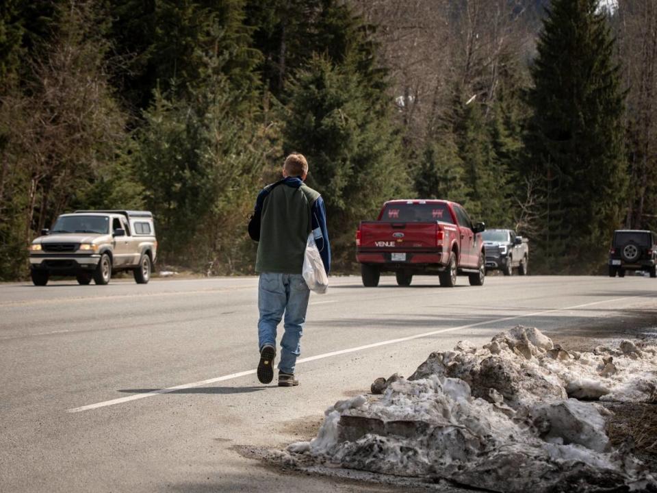 A man walks down Highway 99, the road that connects Squamish, Whistler and Pemberton. Transit drivers in the region have been on strike for months.  (Ben Nelms/CBC - image credit)