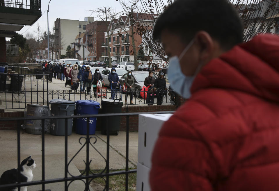 A line of people stretches for two blocks outside the United Sherpa Association's weekly food pantry on Friday, Jan. 15, 2021, in the Queens borough of New York. The pantry began in April with a focus on the Nepalese community, international students and families living in the country without permission. (AP Photo/Jessie Wardarski)