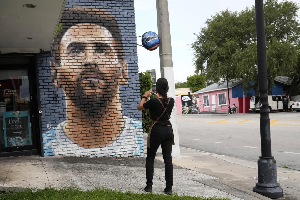 Jessica Ospina takes a photograph of a mural of Lionel Messi outside of the Fiorito restaurant, Wednesday, June 7, 2023, in Miami. The Argentine soccer star announced Wednesday he is joining the Inter Miami Major League Soccer team. (AP Photo/Lynne Sladky)