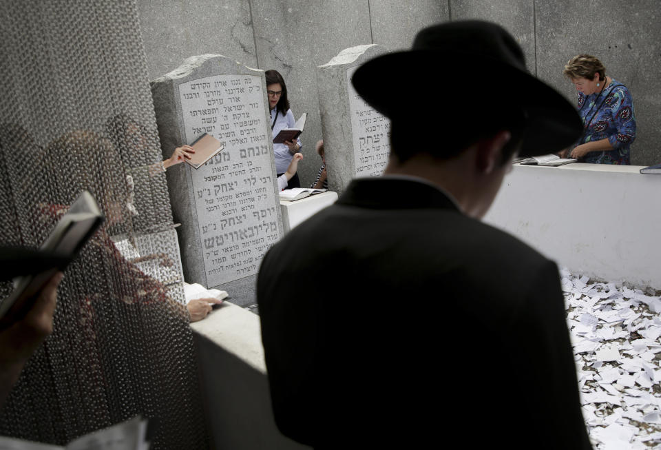 In this July 2, 2019 photo, people pray at the gravesite of Rabbi Menachem M. Schneerson in the Queens borough of New York. For more than four decades, he was one of the most influential global leaders in Judaism, reinvigorating a small community that had been devastated by the Holocaust and pushing for all Jews to become more deeply connected to their faith and do more good in their everyday lives. (AP Photo/Seth Wenig)