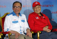 FILE - In this Oct. 8, 2018, file photo, Malaysia's Prime Minister Mahathir Mohamad, right, sits next to Malaysia's reform icon Anwar Ibrahim during a rally in Port Dickson. Political tension is building in Malaysia amid talks that Mahathir will pull his party out of the ruling alliance and team up with opposition parties to form a new government in a major political upheaval. It will thwart his named successor Anwar Ibrahim from taking over. (AP Photo/Vincent Thian)