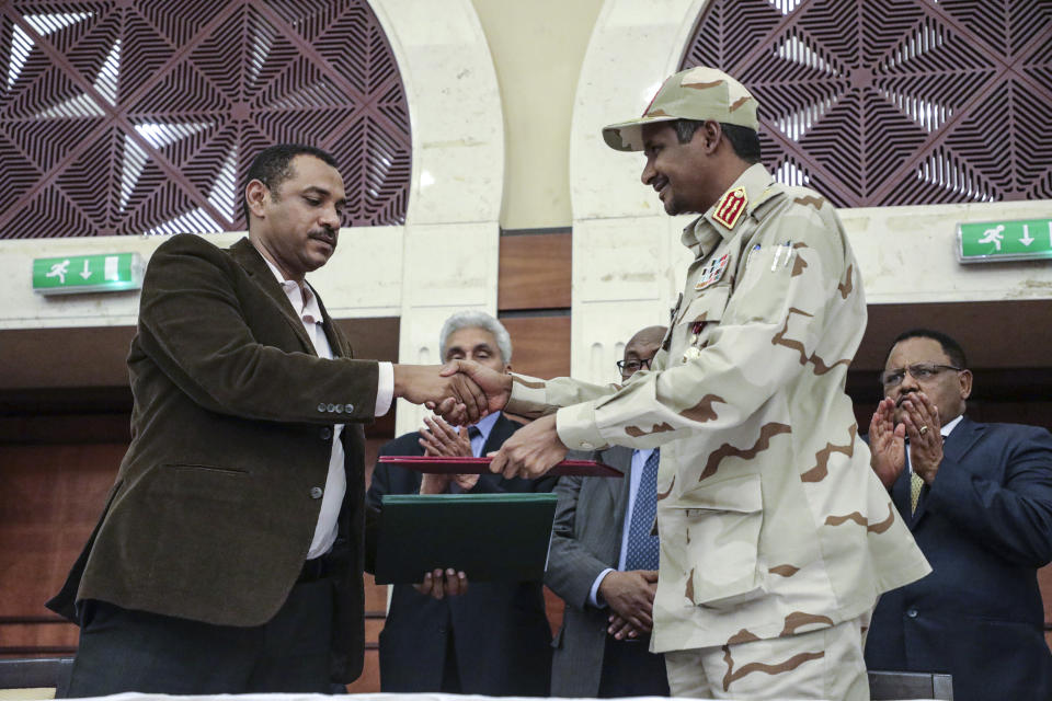 Gen. Mohammed Hamdan Dagalo, right, and Sudan's pro-democracy movement leader Ahmad al-Rabiah shake hands after signing a power sharing document in Khartoum, Sudan, Wednesday, July 17, 2019. The two sides are still at work on a more contentious constitutional agreement that would specify the division of powers. (AP Photo/Mahmoud Hjaj)