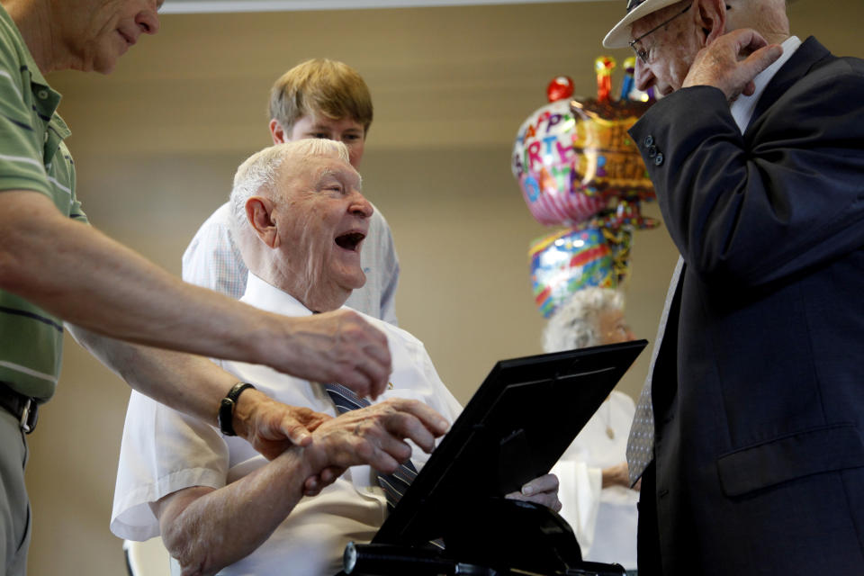 Charles Coolidge, center, laughs after receiving a gift from Luther Massingill during his 90th birthday celebration at Outdoor Chattanooga on Aug. 6, 2011, in Chattanooga, Tenn. The Congressional Medal of Honor Society announced in a statement that Coolidge died Tuesday, April 6, 2021, in Chattanooga. He was 99. Coolidge received the Medal of Honor for actions he took in October 1944 during WWII. (Alex Washburn/Chattanooga Times Free Press via AP)