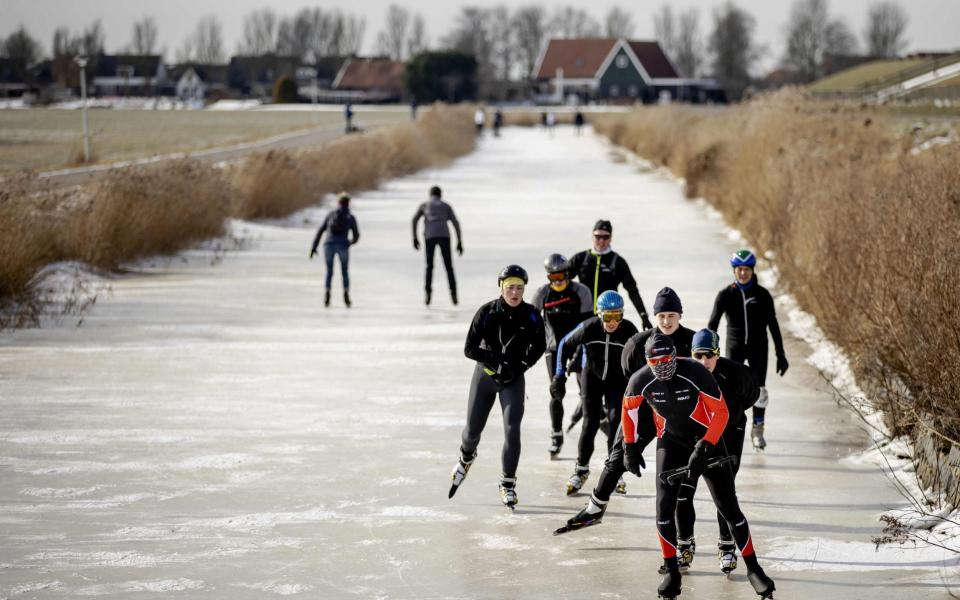  Champion Dutch skater Henk Angenent is followed by others as he glides across ice on a canal at Hindeloopen - Robin van Lonkhussen/AFP