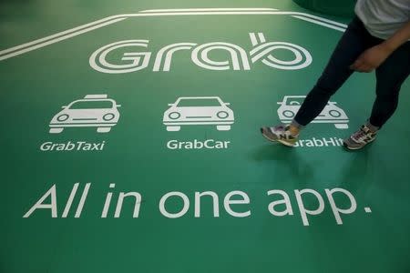 A man passes Grab transport booking service app advertisements at a train station in Singapore February 10, 2016.REUTERS/Edgar Su