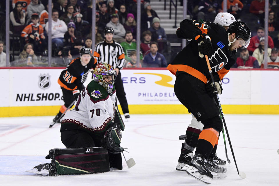 Arizona Coyotes goaltender Karel Vejmelka (70) looks for the puck past a screen from Philadelphia Flyers' Joel Farabee during the second period of an NHL hockey game, Monday, Feb. 12, 2024, in Philadelphia. (AP Photo/Derik Hamilton)