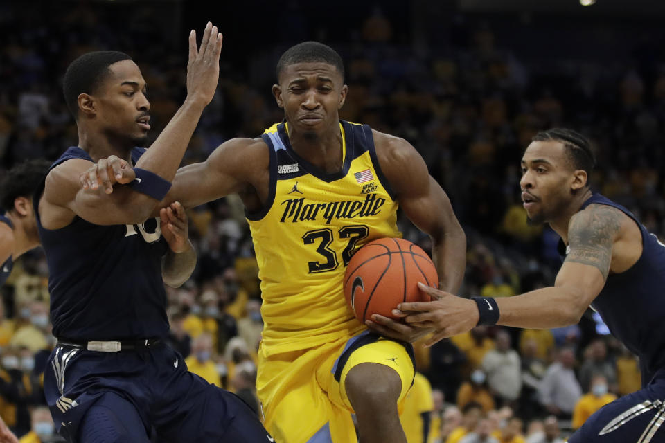 Marquette's Darryl Morsell, middle drives to the basket between Xavier's Nate Johnson, left, and Paul Scruggs, right, during the first half of an NCAA college basketball game Sunday, Jan. 23, 2022, in Milwaukee. (AP Photo/Aaron Gash)