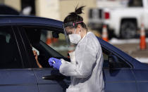 A tester prepares to administer a swab test at a drive-in COVID-19 testing site Tuesday, Oct. 27, 2020, in Federal Heights, Colo. Denver will enforce tighter restrictions for restaurants, retail and offices, reducing maximum capacity from 50 percent to 25 percent amid a spiraling rise in cases of the coronavirus in the state in the past month. (AP Photo/David Zalubowski)