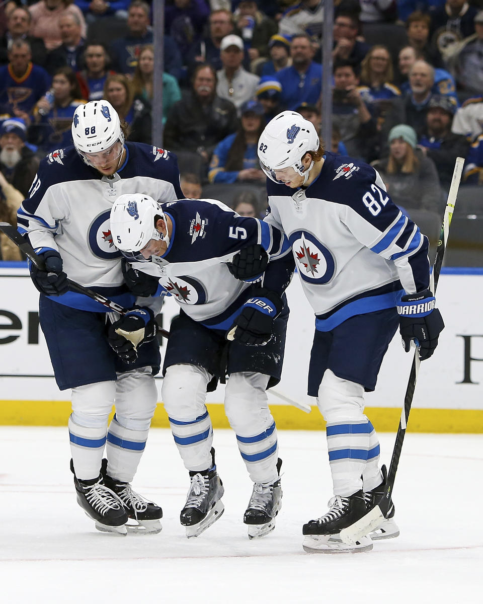 Winnipeg Jets' Nathan Beaulieu (88), left, and Mason Appleton (82), right, help teammate Luca Sbisa (5), of Italy, up from the ice after Sbisa suffered an injury during the second period of an NHL hockey game against the St. Louis Blues, Thursday Feb. 6, 2020, in St. Louis. (AP Photo/Scott Kane)