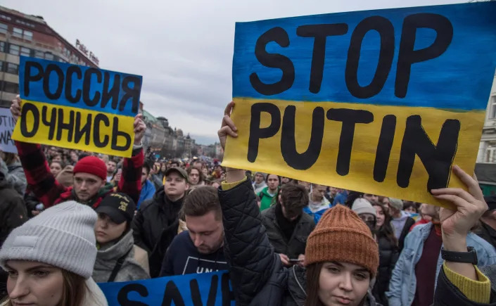 A male demonstrator amid a sea of protesters holds a blue and gold placard saying in Russian, 