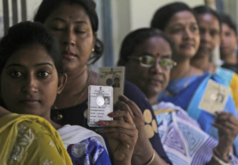 Indian voters display their voter identity cards as they stand in a queue to cast their votes at Podra in Howrah, India, Monday, May 6, 2019. With 900 million of India's 1.3 billion people registered to vote, the Indian national election is the world's largest democratic exercise. (AP Photo/Bikas Das)