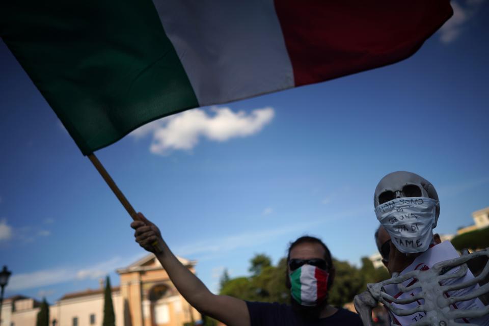 A man waves an Italian flag during a protest against the government restriction measures to curb the spread of COVID-19, in Rome, Saturday, Oct. 10, 2020. (AP Photo/Andrew Medichini)