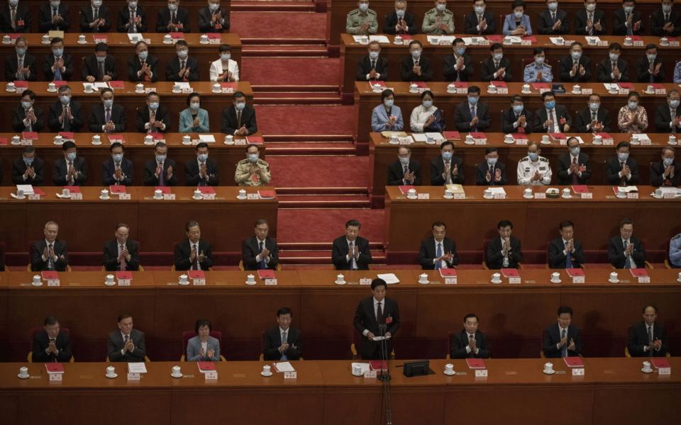 Chinese president Xi Jinping, center, and delegates applaud at the closing session of the National People's Congress