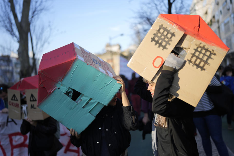 FILE - Two young women wear cardboard houses over their heads during a demonstration protesting Portugal's housing crisis, in Lisbon, Jan. 27, 2024. (AP Photo/Armando Franca, File)