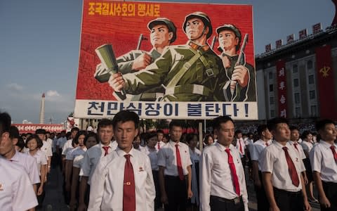 A propaganda poster on display during a rally in support of North Korea's stance against the US - Credit: KIM WON-JIN/AFP/Getty Images