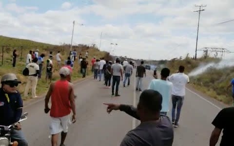 People look on as tear gas this thrown in Santa Elena De Uairen