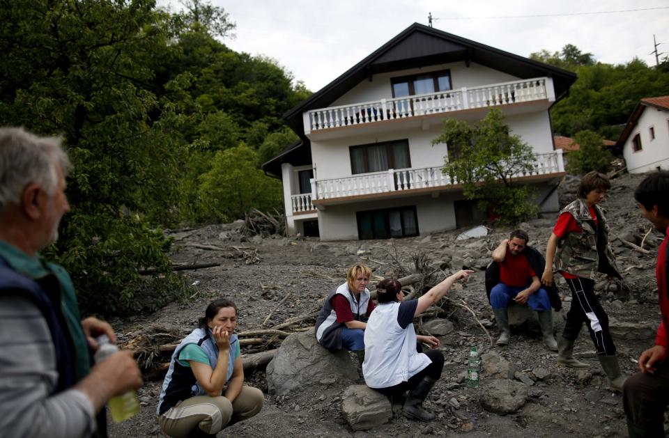 The Kovacevic family sits in front of their flood-damaged house in Topcic Polje