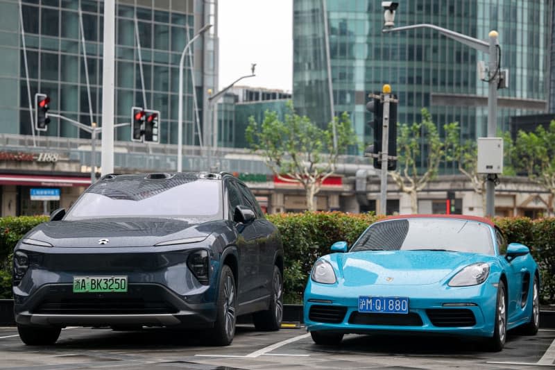 An electric car from the Chinese brand NIO and one from Porsche with a combustion engine are parked in a parking lot. European Union countries on Friday cleared the way for additional tariffs of up to 35.3% on battery-powered electric vehicles imported from China, EU diplomats told dpa. Sebastian Christoph Gollnow/dpa