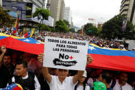 Demonstrators hold Venezuelan flags and a sign reads: ' All the food for all the people! No more dictatorship ' while rallying against Venezuela's President Nicolas Maduro in Caracas, Venezuela May 1, 2017. REUTERS/Carlos Garcia Rawlins