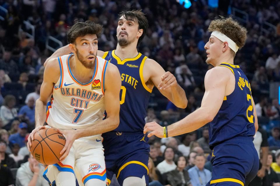 Thunder forward Chet Holmgren (7) drives to the basket against Warriors forward Dario Saric, middle, and guard Brandin Podziemski on Saturday.