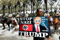 An anti-Trump demonstrator protests as Orange County Sheriff officers stand watch outdoors before Republican U.S. Presidential candidate Donald Trump speaks at a campaign event in Anaheim, California U.S. May 25, 2016. REUTERS/Mike Blake