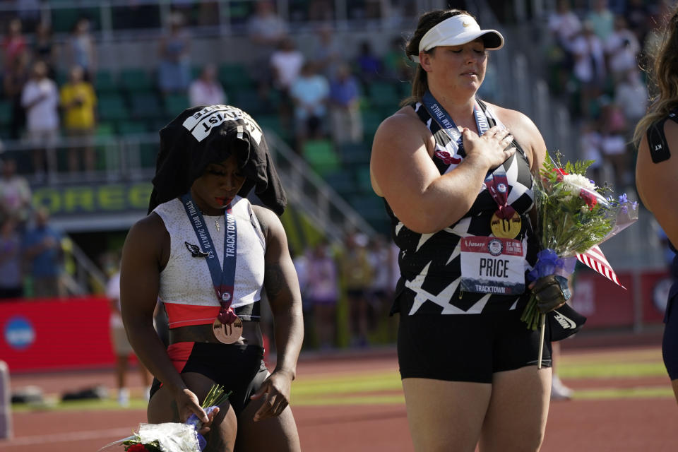 Gwendolyn Berry, left, drapes her Activist Athlete T-Shirt over her head as DeAnna Price stands for the national anthem after the finals of the women's hammer throw at the U.S. Olympic Track and Field Trials Saturday, June 26, 2021, in Eugene, Ore. Price won and Berry finished third. (AP Photo/Charlie Riedel)