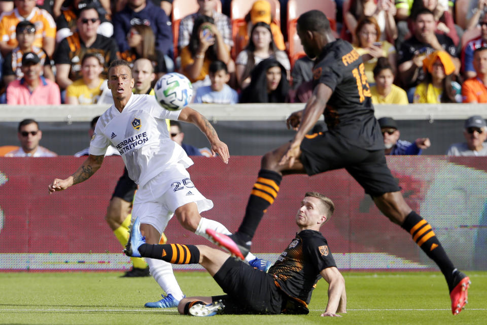 LA Galaxy defender Rolf Feltscher (25) watches as Houston Dynamo defender Adam Lundkvist, middle, slides under the ball as Dynamo defender Maynor Figueroa (15) jumps over Lundkvist during the second half of an MLS soccer match Saturday, Feb. 29, 2020, in Houston. (AP Photo/Michael Wyke)