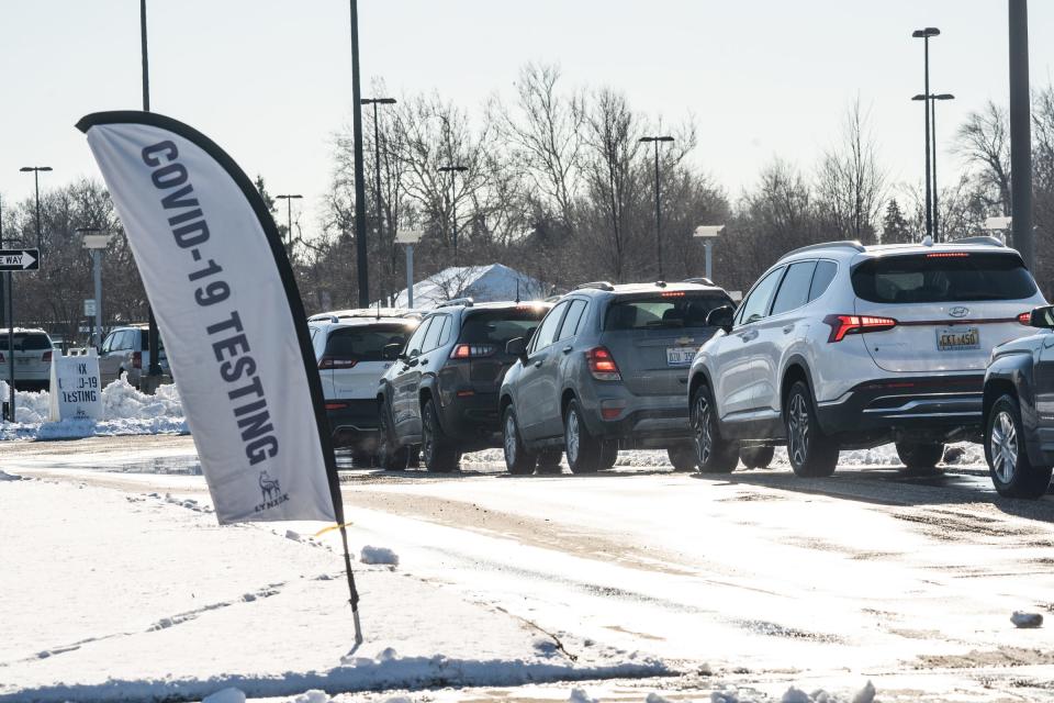 Cars line up along West Outer Drive in Detroit Monday, January 3, 2022, as Detroit Public Community Schools District employees and students wait to take a COVID-19 saliva test at Renaissance High School in Detroit.