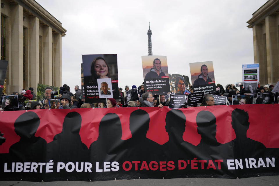 People hold portraits of French detainees in Iran Cecile Kohler, left, and Benjamin Briere during a protest in Paris, Saturday, Jan. 28, 2023. Families and friends of a growing number of Europeans imprisoned in Iran gathered in Paris on Saturday to call for their release. The banner reads : "Freedom for state hostages in Iran". (AP Photo/Thibault Camus)