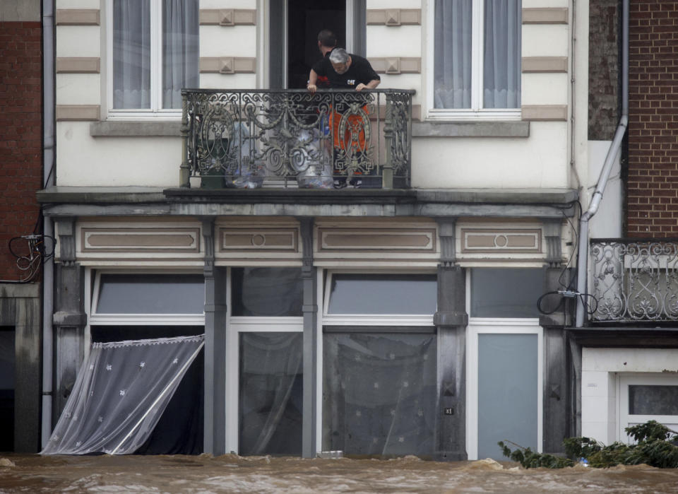 Rescue workers look down from a balcony as floodwaters run down a main street in Pepinster, Belgium, Thursday, July 15, 2021. Heavy rainfall is causing flooding in several provinces in Belgium with rain expected to last until Friday. (AP Photo/Olivier Matthys)